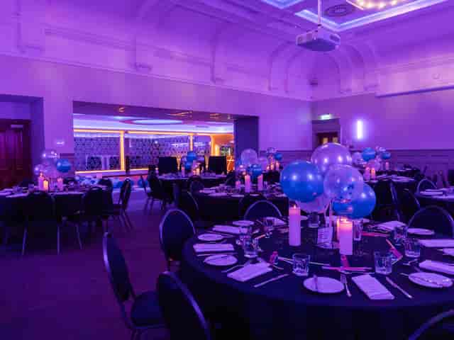 Elegant gala event space with round tables, purple lighting, and festive decor.