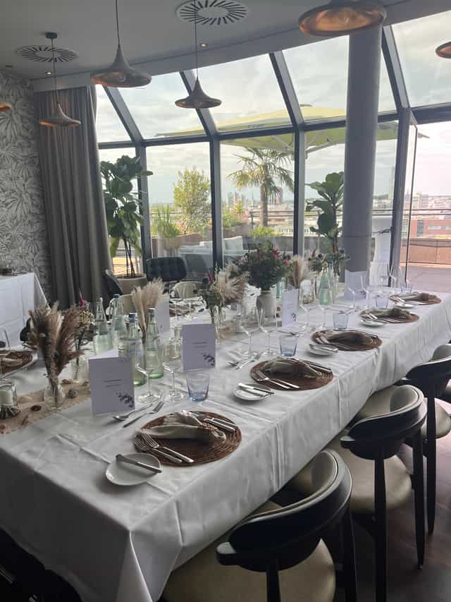 Wasserturm Hotel rooftop dining: elegant executive corporate luncheon setup with city views.
