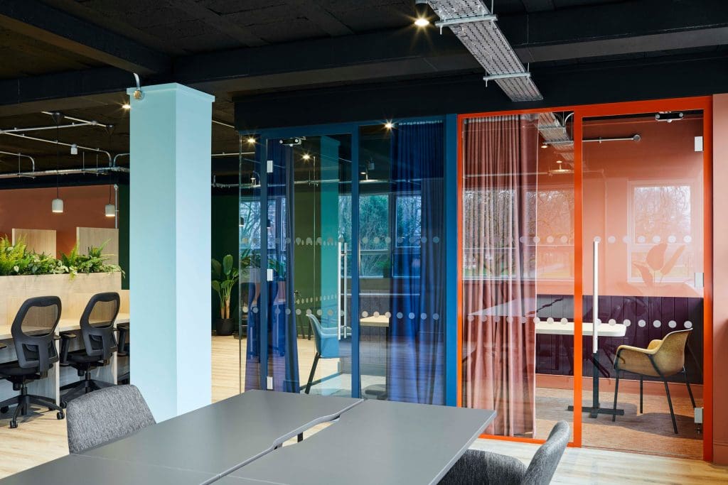 Modern glass breakout rooms for team meetings and collaborative office workspaces.