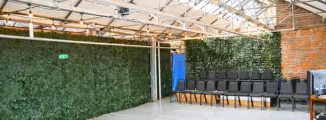 Industrial event space with green wall backdrop for intimate presentations and rehearsals.