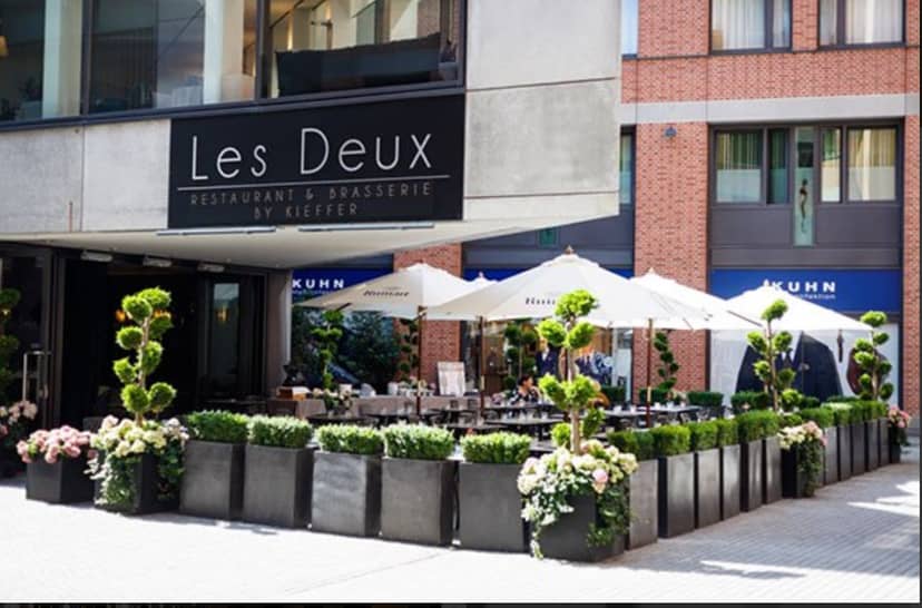 Al fresco corporate reception at Les Deux Brasserie featuring manicured planters for networking.