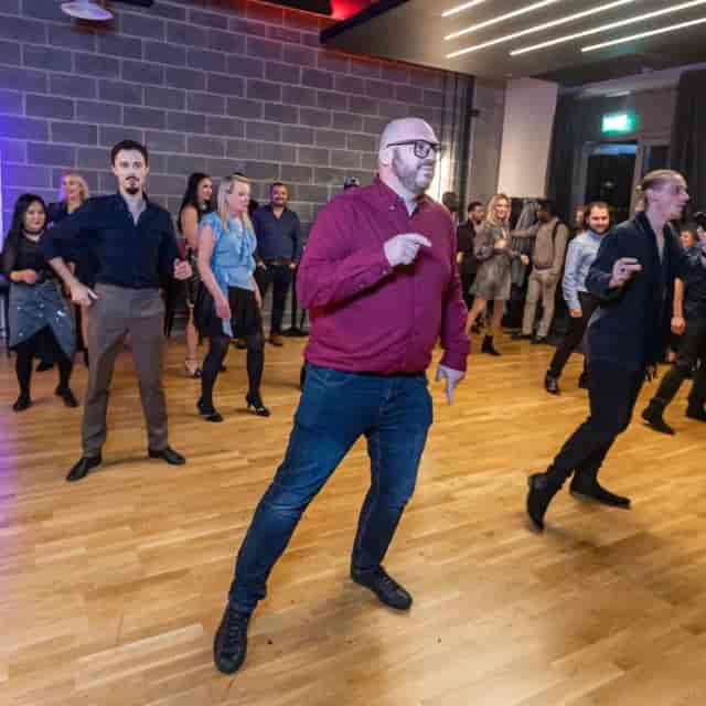 Industrial-chic dance studio hosting a lively evening social event with high attendee engagement.