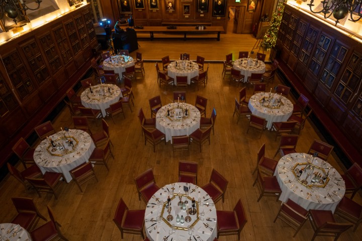 Elegant banquet hall set for Christmas parties with white tablecloths and centerpieces. - Banner