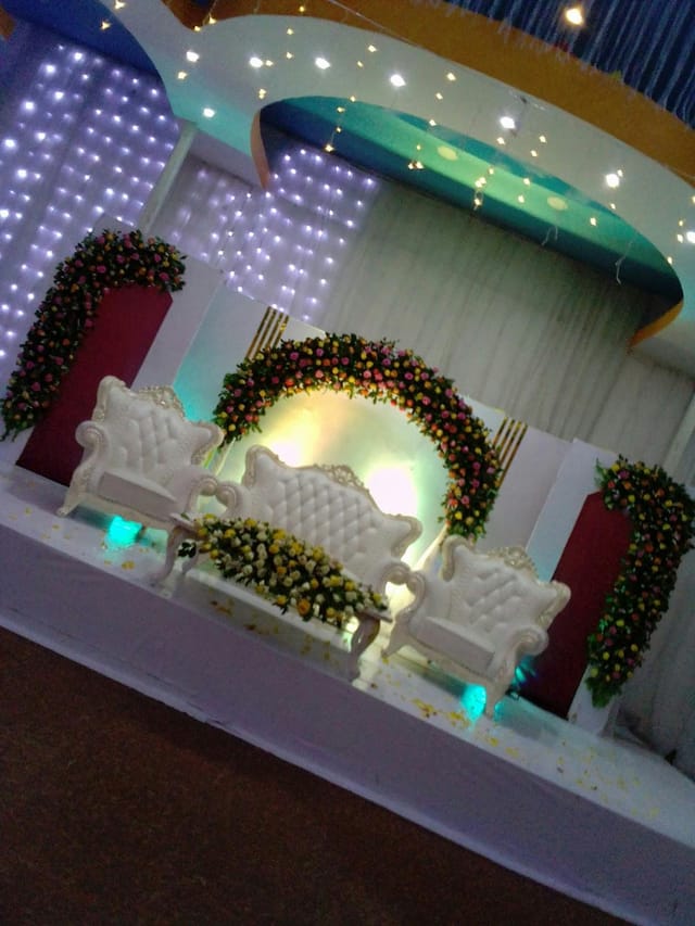 Wedding stage at Lekam Park hall with tufted white seating and floral arches for event decor.
