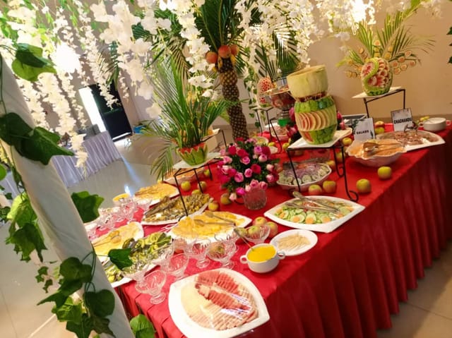 Buffet with fruit carvings and floral decor for premium themed events and catering.