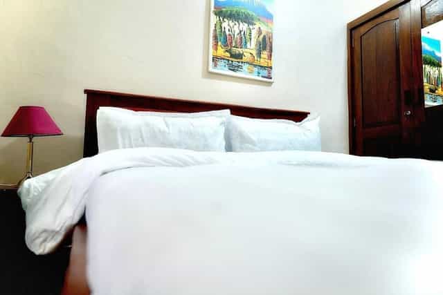 Hotel room in Sixsixty Apartments, Dar es Salaam with wooden headboard for business travel.