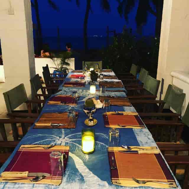 Upepo Garden al fresco private dinner, rustic wooden chairs, outdoor event, romantic dining venue.