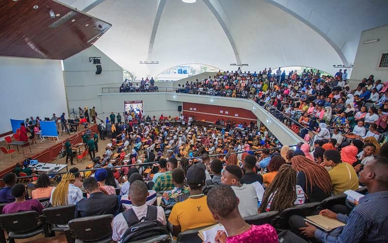Amphitheater meeting room at capacity for a large-scale lecture and plenary session.