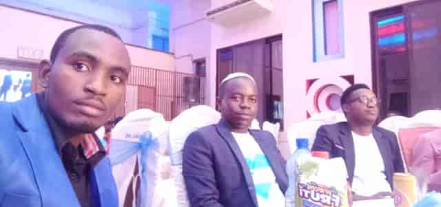 Bishop Nzigilwa at a community gathering, banquet-style corporate event setup.