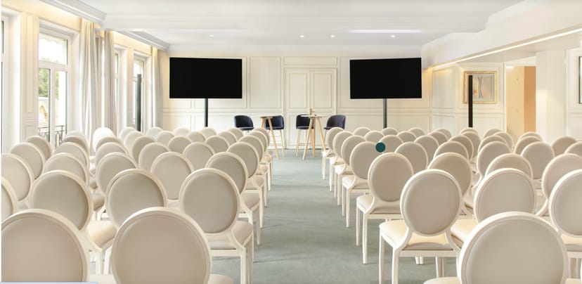 Elegant seminar setup with white chairs and screens at Le Pré Catelan for meetings.