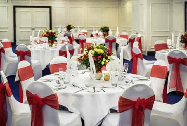 Wedding banquet at Mercure Swansea Hotel with round tables and red sashes for formal event venue.