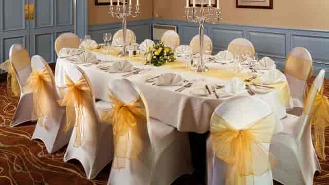Boardroom wedding banquet setup with gold sashes and candelabras at Mercure Livingston Hotel.