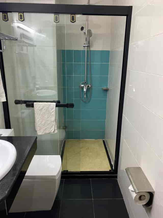Teal-tiled hotel bathroom at Adig Suites Amuwo Odofin, ideal for corporate travel and event stays.