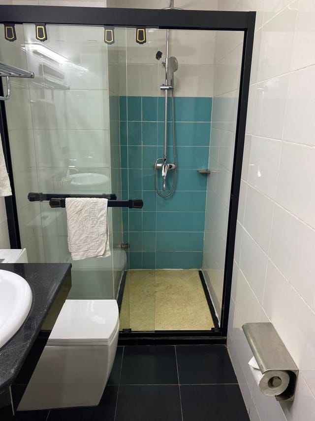 Teal-tiled hotel bathroom at Adig Suites Amuwo Odofin, ideal for corporate travel and event stays.