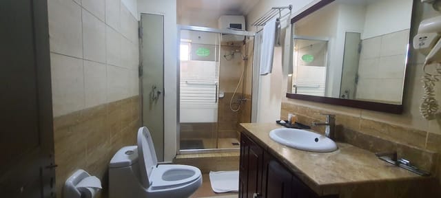 Standard hotel bathroom with dated fixtures, ideal for hospitality renovation and facility audits.
