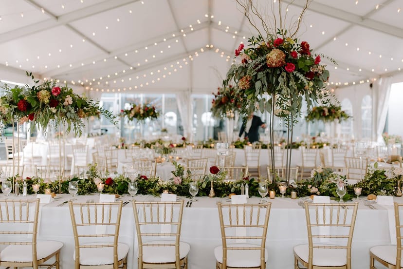 Marquee setup with warm fairy lights and floral centerpieces for an upscale gala or wedding.