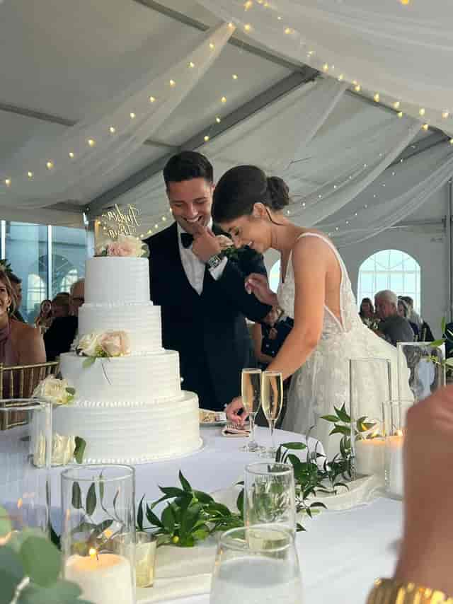 Wedding cake cutting at The Veranda, Lago Custom Events, with elegant bistro-lit tent reception.