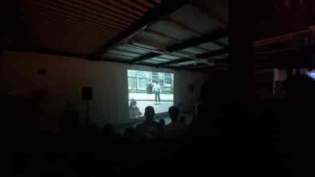 Stryx art gallery event: poorly lit industrial screening space with AV setup.