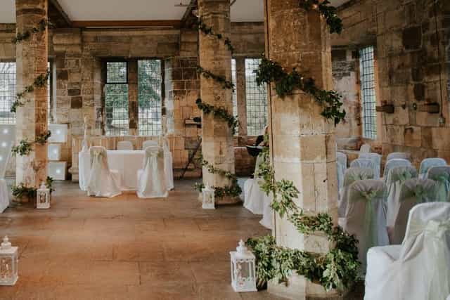 Historic Hospitium wedding venue with stone pillars and elegant ceremony aisle decor.