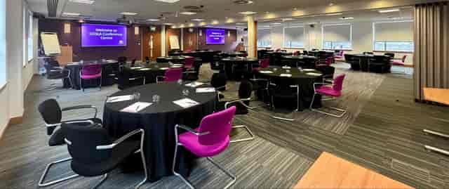 Banquet-style meeting space with fuchsia chairs for corporate conferences and breakout sessions.