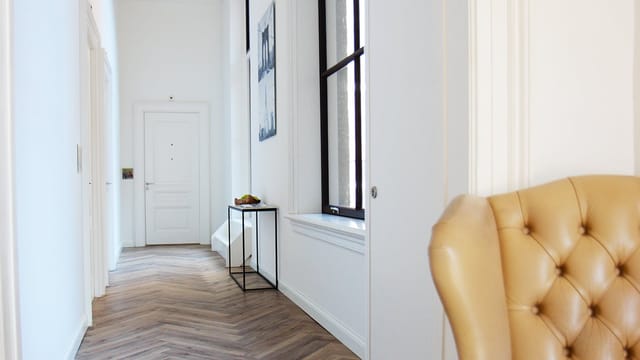 Minimalist Hotel Kop van Zuid suite with herringbone floors for event registration or VIP lounge.