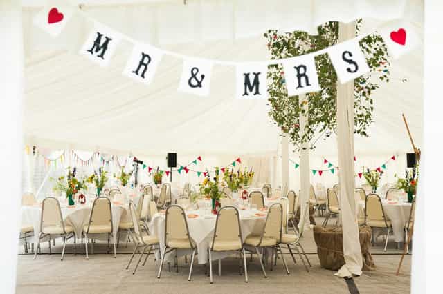 Marquee wedding at Kenton Hall Estate: neutral linens and bunting for budget-friendly celebrations.