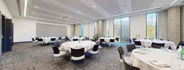 Modern banquet space at INNSIDE Manchester with round tables and natural light.