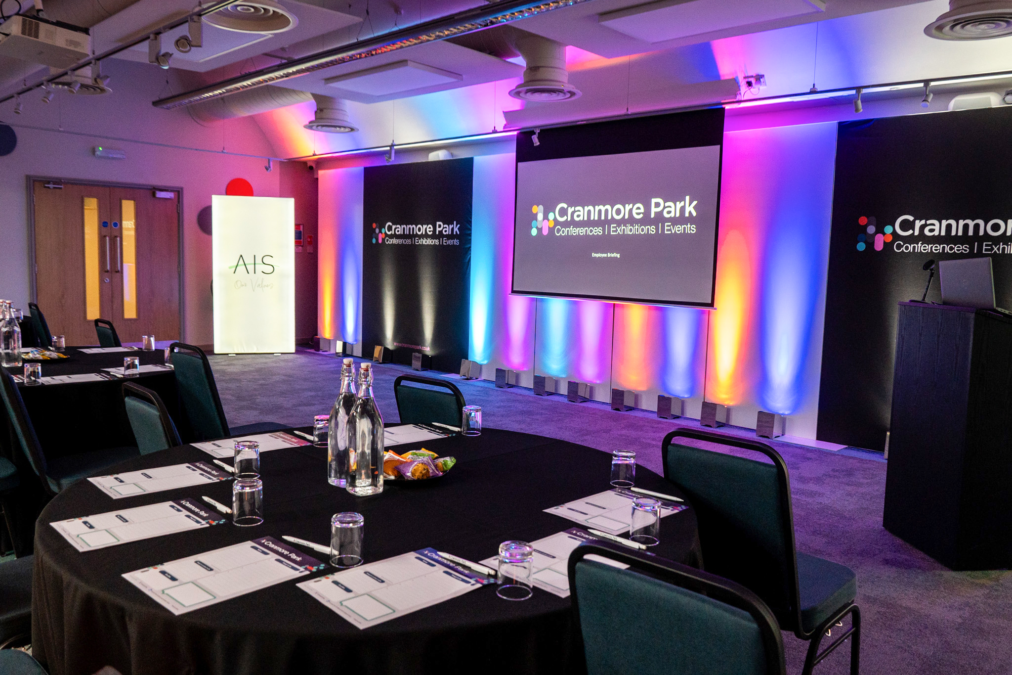 Cranmore Park Gallery Suite meeting room with stage uplighting for corporate conferences. - Banner
