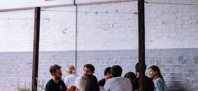Industrial-chic event venue with white brick wall for networking and corporate breakout sessions.