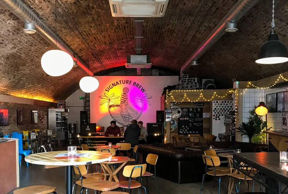 Industrial-chic event venue with exposed brick archway, ideal for networking and team-building.