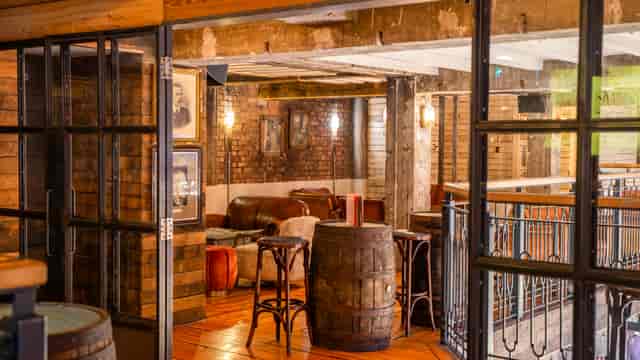 Ludwig's Tavern industrial brick event space with barrel tables for networking and VIP receptions.