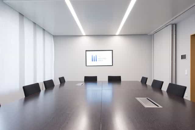 Minimalist executive boardroom with integrated tech for corporate strategy meetings and workshops.
