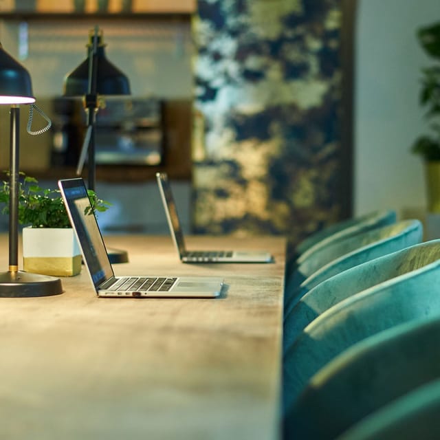Upscale velvet hot desk workspace with lush greenery for collaborative breakout sessions.
