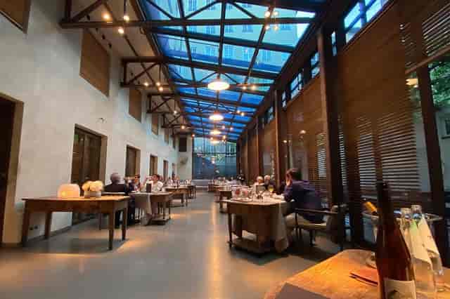 Industrial-chic restaurant venue with glass atrium for elegant dinner or networking events.