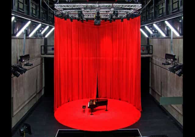 Grand piano on circular riser in Reaktorhalle, perfect for theatrical performances or live concerts.