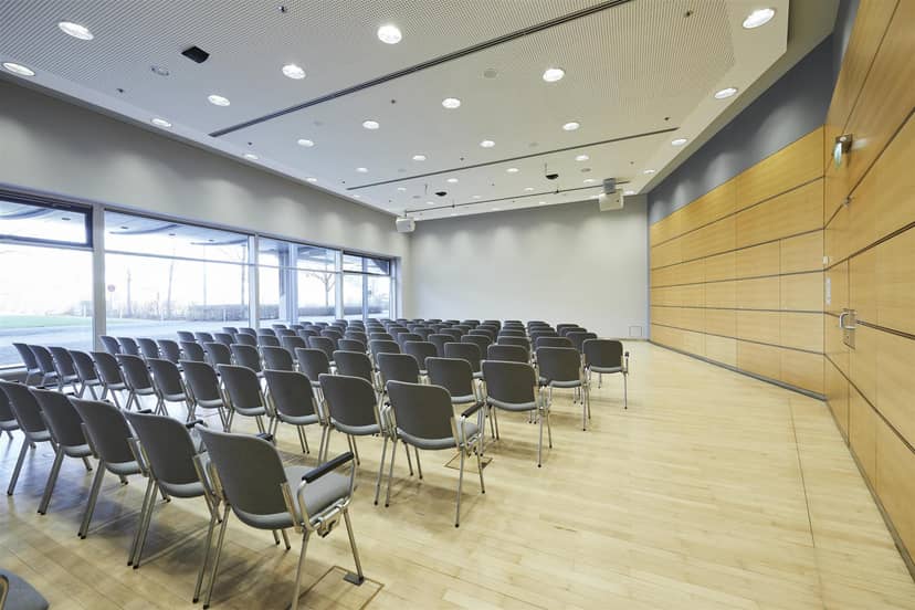 Theater-style corporate event setup in modern, sunlit Hall C6 at Messe München conference center.