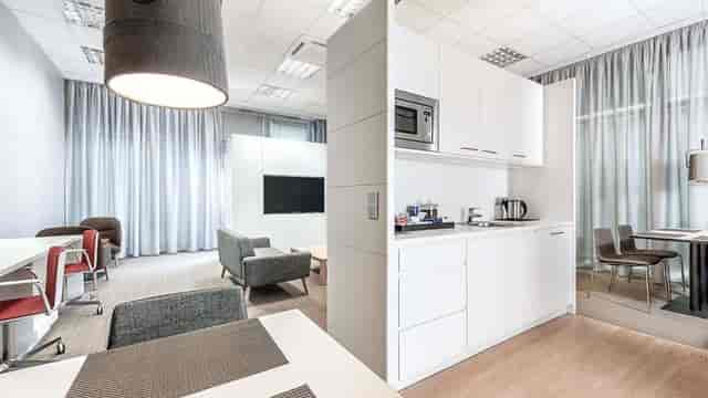 Versatile NH München Ost breakout room with kitchenette for business meetings and networking events.