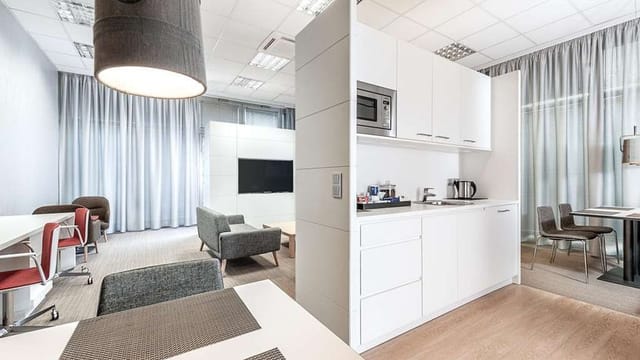 Versatile NH München Ost breakout room with kitchenette for business meetings and networking events.