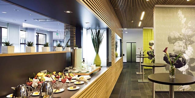Modern hotel refreshment area with wood paneling for corporate networking and coffee break events.