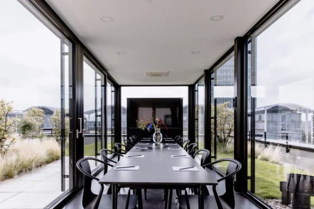 Glass-enclosed rooftop boardroom at THE FLAG München M for executive strategy sessions.