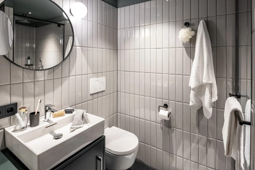 Modern hotel bathroom in Revo Munich, compact contemporary design for business travel stays.