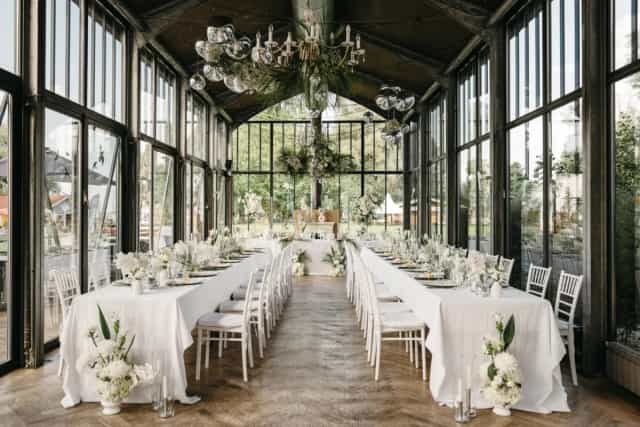 Glass greenhouse event venue with floral decor for luxury weddings and corporate dinners.