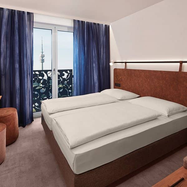Modern H2 Hotel München guest room with twin beds and iconic skyline view for corporate events.