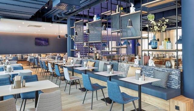 Modern H2 Hotel München cafe with booth seating for corporate networking and business meetings.