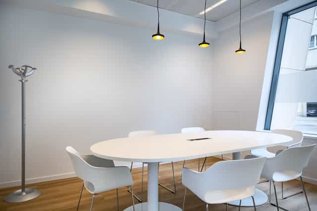 Minimalist breakout room with oval table for intimate brainstorming and private meetings.