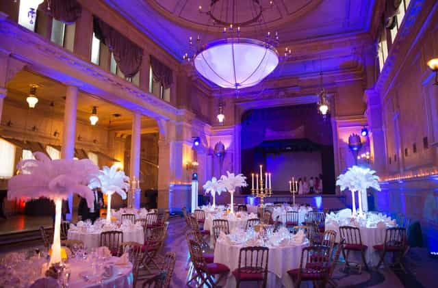 Elegant banquet hall with purple uplighting and ostrich feather decor for gala event venue.