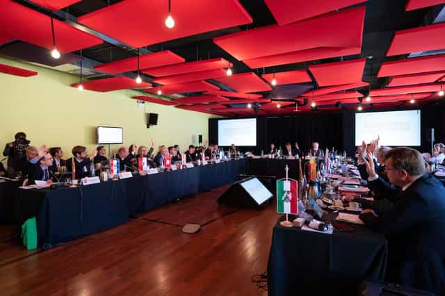 U-shaped boardroom with red acoustic ceiling for professional diplomacy and international events.