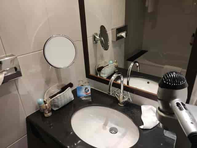 Jacques Tati I hotel bathroom with cluttered vanity, ideal for event planning and venue reviews.