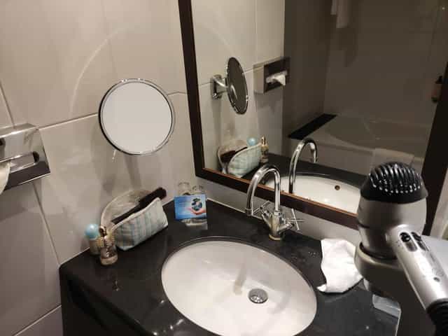 Jacques Tati I hotel bathroom with cluttered vanity, ideal for event planning and venue reviews.