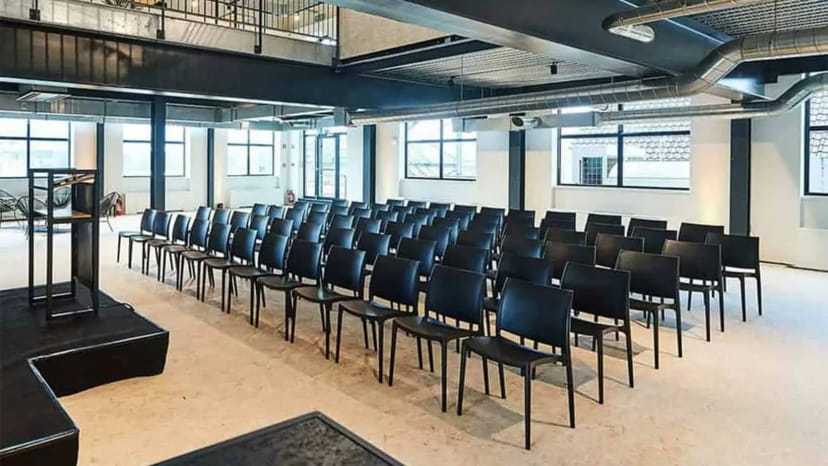 Industrial-chic conference center in theater-style layout for corporate presentation or keynote.